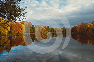 Autumn landscape in overcast weather. - A blue lake and autumn yellow trees on the shores with reflections