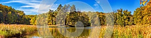 Autumn landscape, panorama, banner - view of a small island on the lake with reflection in the water of autumn trees