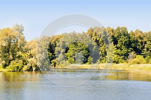 Autumn landscape with river Bank, yellowing forest and blue sky