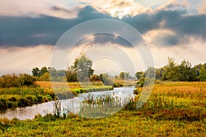 Autumn landscape with river and picturesque dramatic sky during sunset