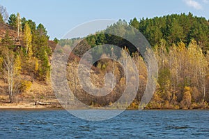 Autumn landscape,  river, windy weather, dark blue water, yellow-red autumn leaves on trees, last warm days