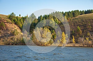 Autumn landscape,   river, windy weather, dark blue water, yellow-red autumn leaves on trees, last warm days