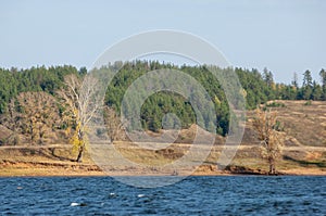 Autumn landscape,   river, windy weather, dark blue water, yellow-red autumn leaves on trees, last warm days