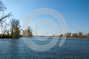 Autumn landscape,   river, windy weather, dark blue water, yellow-red autumn leaves on trees, last warm days