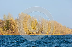 Autumn landscape,   river, windy weather, dark blue water, yellow-red autumn leaves on trees, last warm days