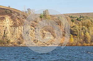 Autumn landscape,  river, windy weather, dark blue water, yellow-red autumn leaves on trees, last warm days