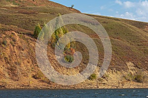 Autumn landscape,   river, windy weather, dark blue water, yellow-red autumn leaves on trees, last warm days