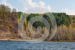 Autumn landscape,  river, windy weather, dark blue water, yellow-red autumn leaves on trees, last warm days