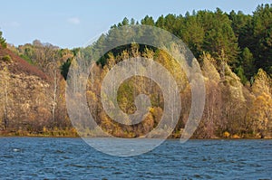 Autumn landscape,  river, windy weather, dark blue water, yellow-red autumn leaves on trees, last warm days