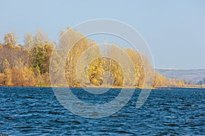 Autumn landscape,   river, windy weather, dark blue water, yellow-red autumn leaves on trees, last warm days