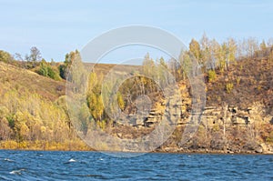 Autumn landscape,   river, windy weather, dark blue water, yellow-red autumn leaves on trees, last warm days