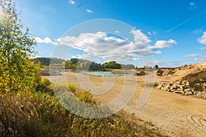 Autumn landscape. Sand pit. Lake and yellow trees.