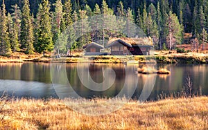 Autumn landscape with traditional norwegian wooden mountain cottage with grass on the roof by the river. Shallow depth