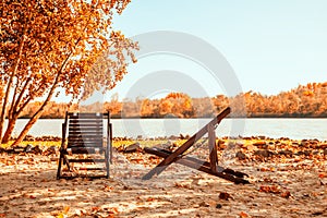 Autumn landscape with two chairs on the sandy river bank