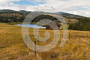 Autumn lanscape of a rustic wooden house on the river or lake bank, surrounded by a beautiful forest. Autumn landscape