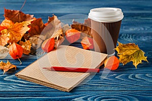 Autumn leaves, hot steaming cup of coffee and on wooden table ba