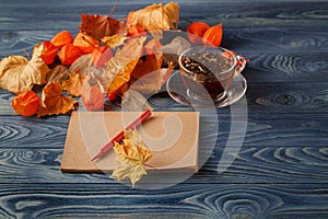 Autumn leaves, hot steaming cup of coffee and on wooden table ba