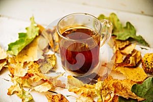 Autumn leaves and hot steaming cup of coffee. Wooden table on sun light background. Fall time concept.