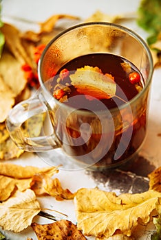 Autumn leaves and hot steaming cup of coffee. Wooden table on sun light background. Fall time concept.