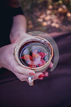 Autumn leaves and hot steaming cup of herbal tea with leave in woman hand. Fall season, leisure time and tea time break concept