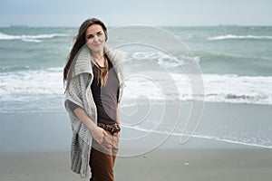 Autumn lifestyle fashion portrait of young stylish hipster woman walking on a sea beach
