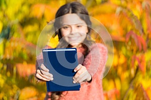 Autumn literature concept. Small child enjoy reading autumn foliage background. Little child enjoy learning in autumn