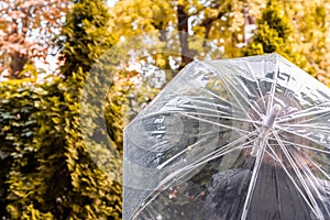 Autumn. Lonely redhead girl under a transparent umbrella with rain drops walking in a park, garden. Rainy day landscape.