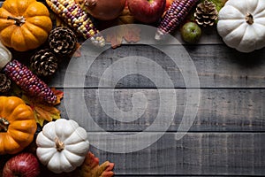 Autumn maple leaves with Pumpkin, apple, corn and red berries on old wooden background. Thanksgiving day concept