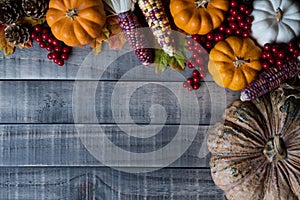 Autumn maple leaves with Pumpkin, apple, corn and red berries on old wooden background. Thanksgiving day concept