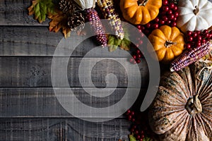 Autumn maple leaves with Pumpkin, apple, corn and red berries on old wooden background. Thanksgiving day concept