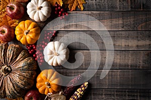 Autumn maple leaves with Pumpkin, apple, corn and red berries on old wooden background. Thanksgiving day concept