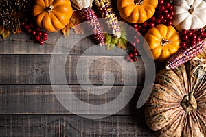 Autumn maple leaves with Pumpkin, apple, corn and red berries on old wooden background. Thanksgiving day concept