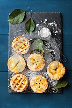 Autumn mini apple pies on black slate board top view. Tasty pastry desserts.