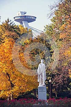 Jesenná nálada výhľad na mestský park, farebné jesenné lístie na obrovských stromoch, socha Janka Kráľa a dominanta UFO veže v Bratislave
