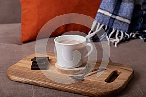 Autumn mood composition with cup of cocoa and chocolate, plaid and books on sofa background. Hot drink in autumn concept