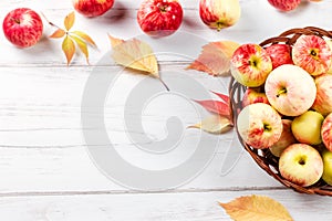 Autumn mood composition with red apples in wicker basket and yellow leaves