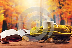 Autumn mood - opened book, scarf and hot drink on the table