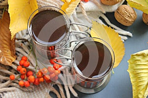 Autumn morning with a Cup of tea. A Cup of tea on a plaid background, surrounded by yellow leaves