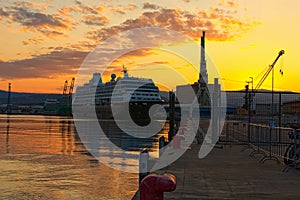 Autumn morning in the international harbor of Koper. Moored huge luxury cruise ship. Big harbor`s cranes ready for work.