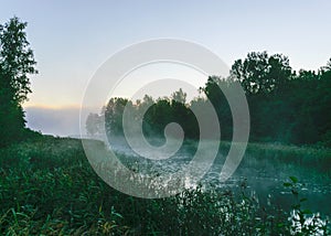 autumn morning by the lake, fog over the surface of the water, a moment before sunrise