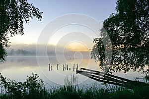 autumn morning by the lake, fog over the surface of the water, a moment before sunrise