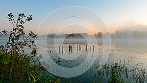 autumn morning by the lake, fog over the surface of the water, a moment before sunrise