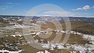 Autumn morning in mountains, yellow grass and snow covered. Clip. Aerial view of growing coniferous forest and snowy