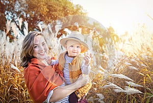 Autumn. Mother and baby boy (child, kid) having fun outdoors on the fall city park.