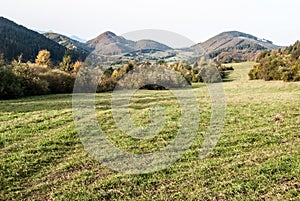 Jesenná horská krajina s lúkami, stromami a kopcami