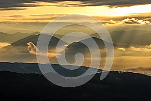 Autumn mountain landscape at sunrise. Foggy morning.Golden light. Sunbeams shining through the clouds