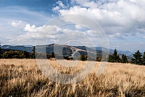 Autumn mountain meadow with hlls on the background and blue sky with clouds