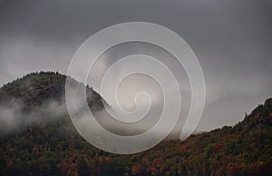 Autumn in the mountains. Mountains overgrown with colorful trees in the fog. USA. Maine.