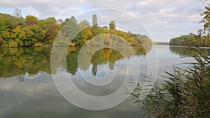 Autumn nature on the shores of the Southern Bug. The calm flow of the river. Reflection in the water of the sky and trees