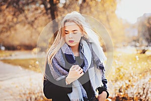 Autumn outdoor casual portrait of young beautiful woman walking in park in warm fashion outfit